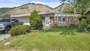 View of front of property featuring an attached garage, a front yard, a mountain view, and brick siding