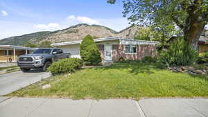 View of front of house featuring a mountain view, an attached garage, a front lawn, and concrete driveway