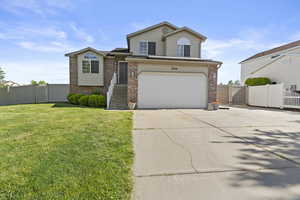 View of front of property featuring brick siding, concrete driveway, an attached garage, and a gate
