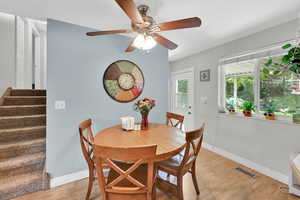 Dining space featuring ceiling fan, laminate wood floors, and stairway