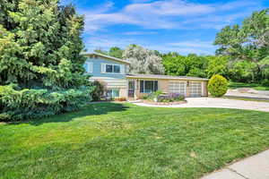 Split level home with brick siding, a front yard, and a 2 car garage