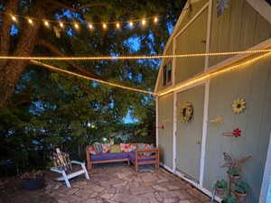 View of patio / terrace next to storage/yard shed at night with lighting