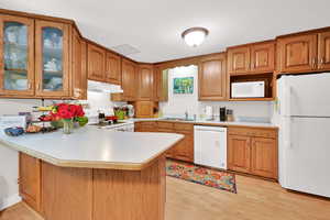 U Shaped Kitchen with white appliances, free standing range, range hood, and light colored laminate countertops