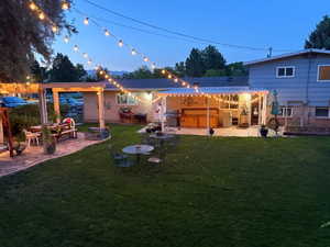 Backyard with lights in the evening, patio bar, pergola, stone pavers