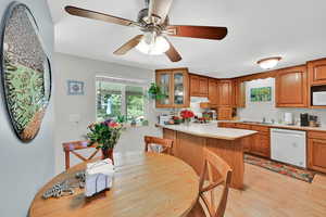 U Shaped Kitchen with white appliances, free standing range, range hood, glass insert cabinets, and brown cabinetry