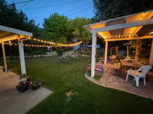 Backyard with lights in the evening, patio bar, pergola, stone pavers