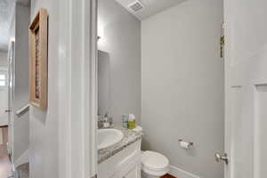 Bathroom featuring vanity, toilet, and baseboards