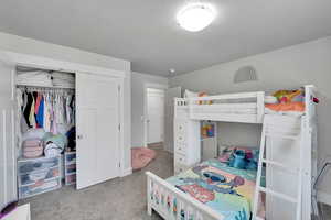 Carpeted bedroom featuring a textured ceiling and a closet