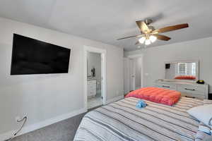 Bedroom with carpet flooring, baseboards, ceiling fan, and ensuite bathroom
