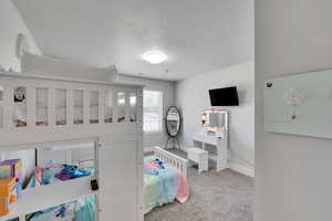 Carpeted bedroom featuring baseboards and a textured ceiling