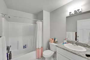 Full bath featuring marble finish flooring, vanity, toilet, shower / bath combination with curtain, and a textured ceiling