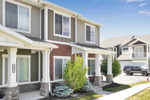 View of front of home featuring covered porch, stone siding, board and batten siding, and cooling unit