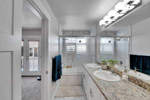 Full bathroom with plenty of natural light, double vanity, a textured ceiling, and marble finish flooring