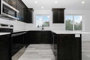Kitchen featuring stainless steel appliances, a peninsula, light countertops, recessed lighting, and light wood-style flooring