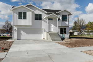 Bi-level home featuring an attached garage, board and batten siding, and concrete driveway