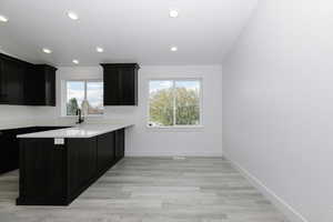 Kitchen with healthy amount of natural light, recessed lighting, light countertops, a peninsula, and baseboards