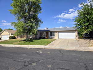 Ranch-style house with an attached garage, a front lawn, and driveway