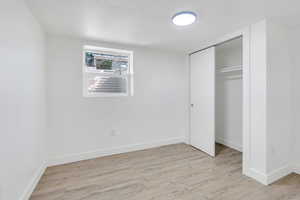 Unfurnished bedroom with light wood-style floors, a closet, baseboards, and a textured ceiling