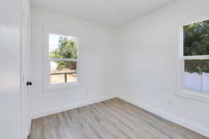 Spare room featuring healthy amount of natural light, light wood-style flooring, and baseboards