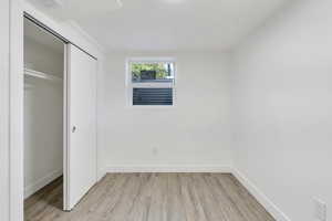 Unfurnished bedroom with light wood-type flooring, a closet, and baseboards
