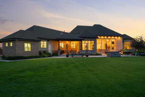 Rear view of property featuring a fire pit, a patio, a yard, brick siding, and roof with shingles