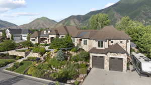 View of front of home with stone siding, concrete driveway, an attached garage, and a mountain view