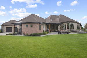 Rear view of house featuring a yard, a patio area, roof with shingles, and a garage