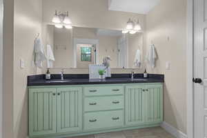 Bathroom featuring double vanity, baseboards, and tile patterned floors