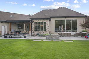 Rear view of property with an outdoor living space, a patio, roof with shingles, stucco siding, and a lawn