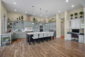 Kitchen featuring stainless steel appliances, a breakfast bar, decorative backsplash, open shelves, and light wood-type flooring