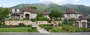 French country home featuring a mountain view, stone siding, stucco siding, a garage, and a front lawn