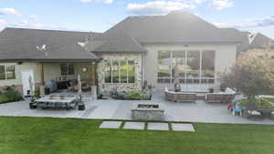 Back of property featuring an outdoor living space with a fire pit, a patio, a lawn, and stucco siding