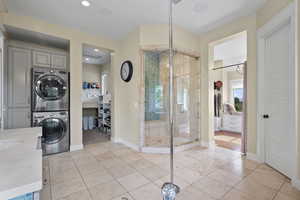Full bathroom featuring stacked washer / drying machine, a stall shower, tile patterned flooring, baseboards, and recessed lighting