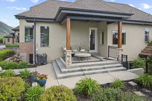 Back of property with a ceiling fan, stucco siding, a shingled roof, and a mountain view