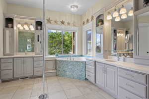 Full bathroom featuring two vanities, a bath, and tile patterned flooring