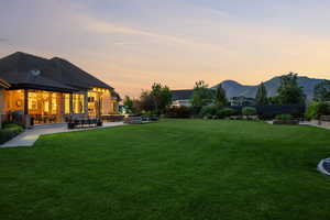 Yard at dusk featuring a mountain view and a patio area