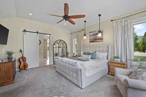 Bedroom with a barn door, lofted ceiling, multiple windows, carpet floors, and recessed lighting