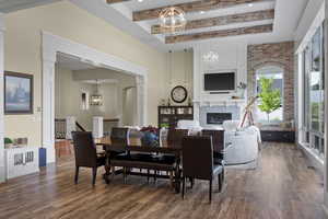Dining room with a chandelier, wood finished floors, a glass covered fireplace, and beam ceiling
