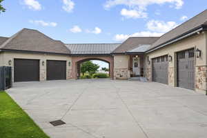 View of front of property with driveway, an attached garage, a standing seam roof, and metal roof