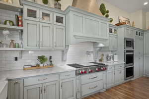 Kitchen featuring open shelves, appliances with stainless steel finishes, light countertops, and backsplash