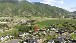 Aerial view of property and surrounding area featuring a mountainous background and nearby suburban area
