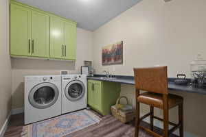 Laundry area featuring washing machine and dryer, cabinet space, dark wood-style flooring, and baseboards