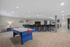 Game room with light colored carpet, wet bar, and recessed lighting