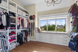 Spacious closet featuring a chandelier and light wood finished floors