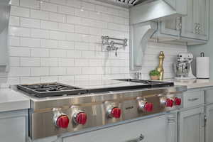 Kitchen with stainless steel gas cooktop, decorative backsplash, and light countertops