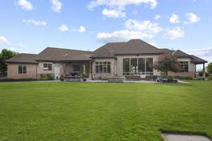 Rear view of house with a patio area, a lawn, outdoor lounge area, and brick siding