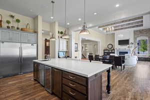 Kitchen with built in fridge, open floor plan, wine cooler, dark wood finished floors, and light countertops