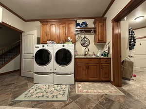 Washroom with cabinet space, ornamental molding, and washer and clothes dryer