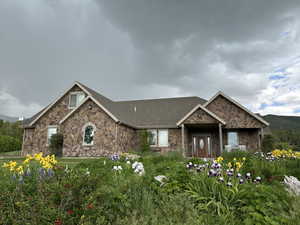 Craftsman inspired home featuring stone siding and a shingled roof