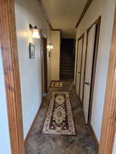 Corridor with crown molding, baseboards, and stone finish flooring